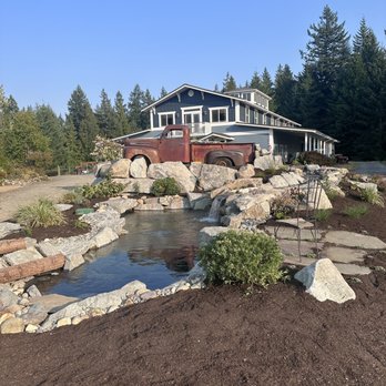 Zenji Landscape Construction - a house with a pond in front of it - Landscaping Near Me