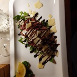 A slices Angus with a side of rocket and parmasian