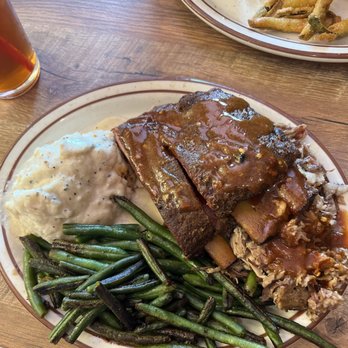 Greg's BBQ - 2meat combination plate rib and pulled pork - A plate features slow-cooked ribs with barbecue sauce, mashed potatoes with black pepper, and sautéed green beans, served on a wooden table. - Barbeque Near Me - Belen, New Mexico