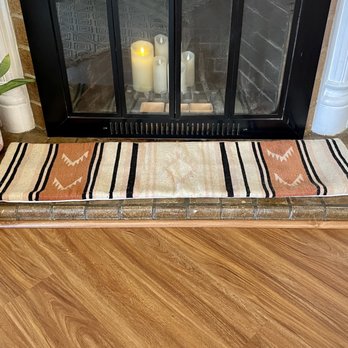 Finesse Handyman - Installing matching vinyl quarter-round trim for floating flooring around fireplace brick. After. - Handyman Near Me Finesse Handyman - Installing matching vinyl quarter-round trim for floating flooring around fireplace brick. After. - Handyman Near Me