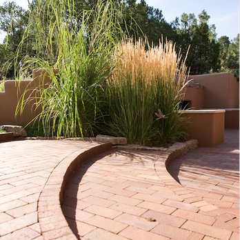EcoScapes - a brick patio with a curved bench - Landscaping Near Me