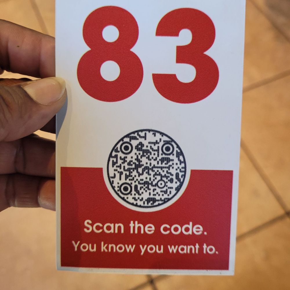 a person holding a sign that reads 83 scan the code you know you want to a person holding a sign that reads 83 scan the code you know you want to