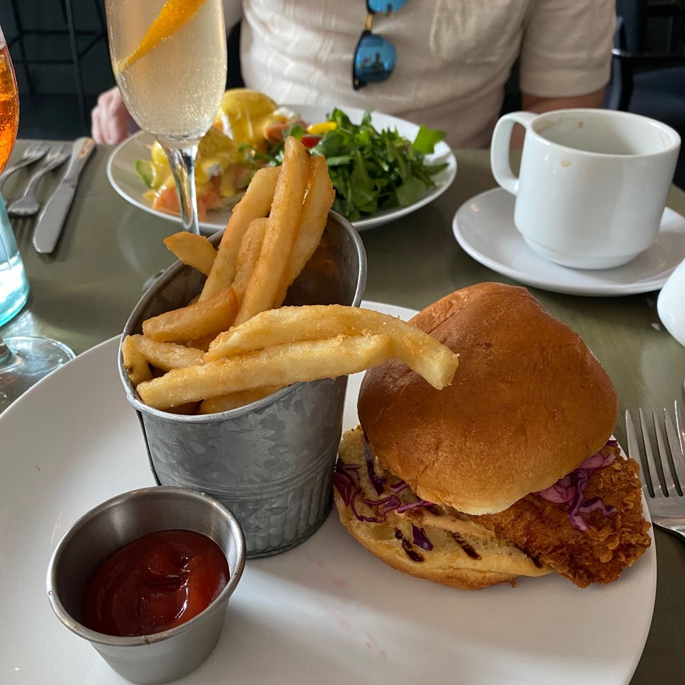 Maison Cheryl - Spicy fried chicken sandwich (eggs royale in the background) - French Near Me - Arlington, Virginia
