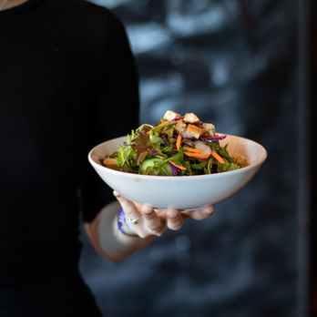 Swans Pub - a woman holding a bowl of salad - Pubs Near Me - Victoria, British Columbia