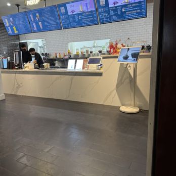 TP Tea - A tea shop counter with digital menu screens, staff preparing beverages, and a white marble counter in a contemporary setting. - Bubble Tea Near Me - Millbrae, California