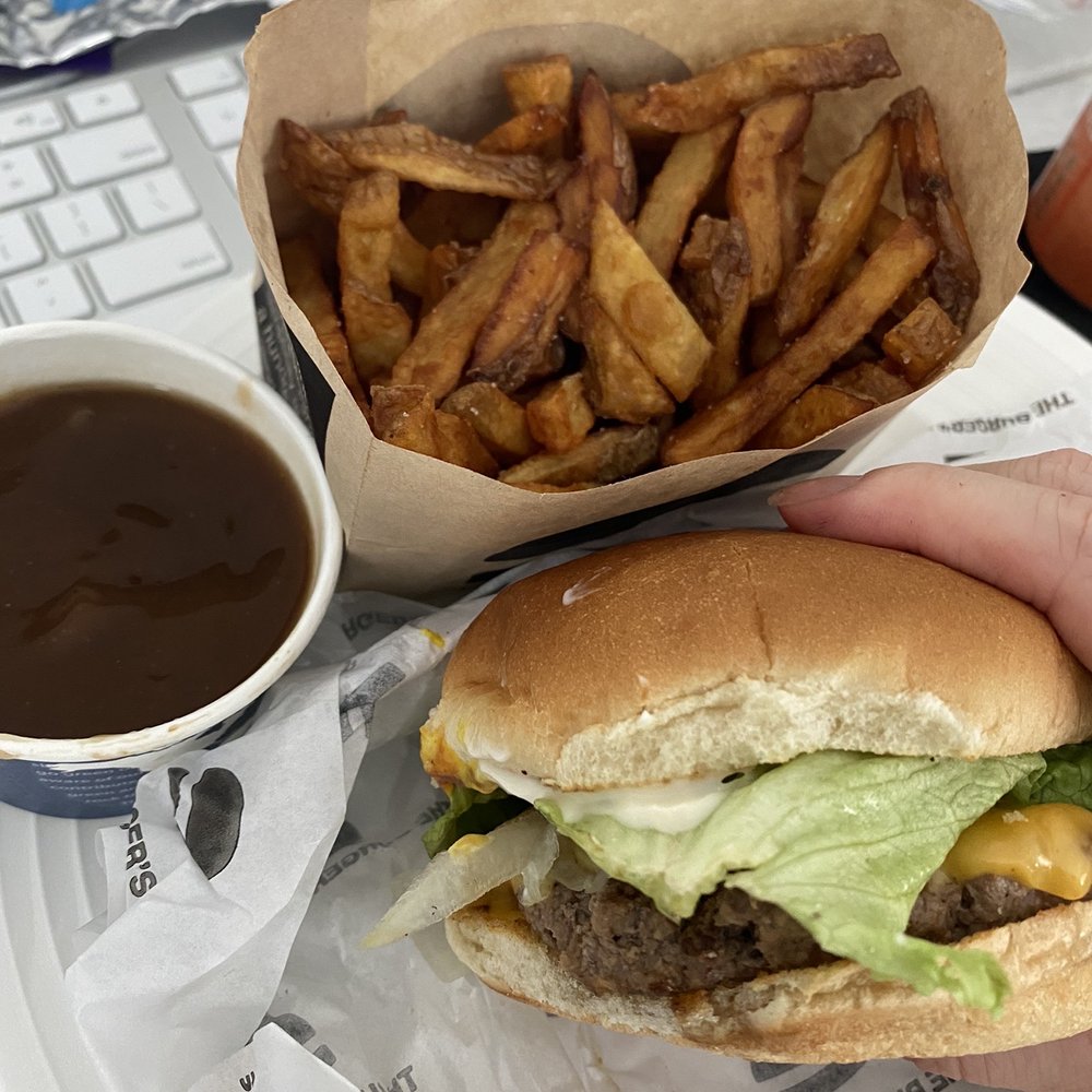 a hand holding a hamburger and fries a hand holding a hamburger and fries