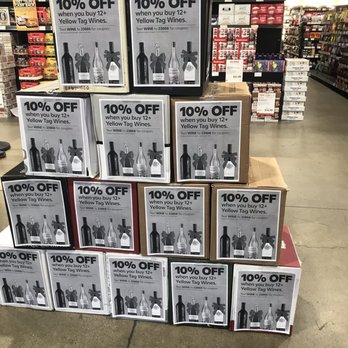 BevMo! - Wine specials - Multiple boxes of wine with promotional signs offering 10% off when purchasing 12 or more bottles are arranged on the store floor. - Beer, Wine & Spirits Near Me - Stockton, California