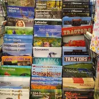 Tractor Supply - 2024 Calendars, an excellent variety. - The image shows a large, multi-tiered calendar display at Tractor Supply in Albuquerque, NM. The display includes a variety of themed calendars such as animals, tractors, and hobbies, arranged in rows. A prominent red sign at the top advertises a 20% discount on 2024 calendars. The calendars feature images of animals, farm equipment, and other subjects, with some titles visible like 'Australian Shepherds,' 'Tractors,' and 'Yoga Dogs.' The display is situated indoors, with other store fixtures partially visible around it. - Livestock Feed & Supply Near Me - Albuquerque, New Mexico