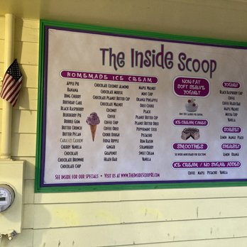 The Inside Scoop - List of flavors - The menu board for The Inside Scoop ice cream shop lists various flavors and options, including homemade ice cream, yogurt, sorbet, and smoothies. It features sections for different types of treats such as ice cream cakes and no-sugar-added options. The board is framed in green and purple, with a small image of an ice cream cone, and is mounted on a yellow wall. An American flag is visible to the left of the board, and a utility meter is mounted below it. - Ice Cream & Frozen Yogurt Near Me - North Kingstown, Rhode Island