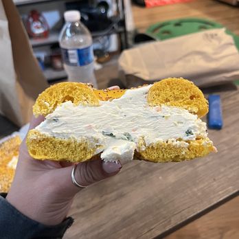 Bagelicious Cafe - a person holding a bagel with cream cheese - Bagels Near Me - Port Jefferson Sta, New York Bagelicious Cafe - a person holding a bagel with cream cheese - Bagels Near Me - Port Jefferson Sta, New York