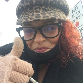 Upland Diner - Love it - A woman wearing glasses, a leopard print hat, and a black face mask pulled down is giving a thumbs-up gesture outdoors. - Diners Near Me - Upland, Pennsylvania