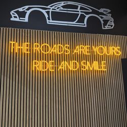 Palladium Autos - Illuminating wall saying the roads are yours ride and smile