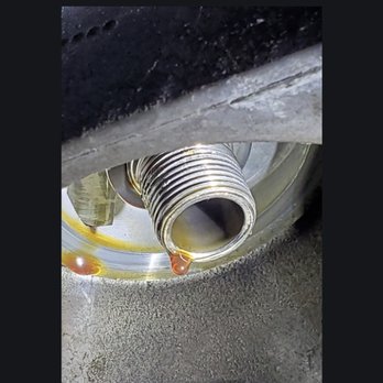 Jiffy Lube - A close-up image shows oil leaking from a threaded metal pipe or fitting, likely part of a mechanical or automotive system. - Oil Change Stations Near Me - Plainfield, Illinois