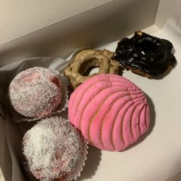 Donuts, concha and a strawberry jam/coconut flakes covered cake.