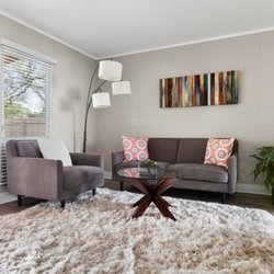 Living room showing a glimpse of a sliding door. Lounge furniture around large white rug.