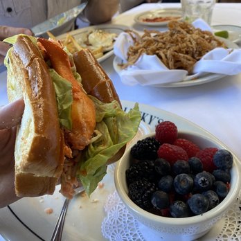 Lucky's - Malibu - Lobster Roll, "Skinny" onion rings, fruit, eggs Benedict in the background. - Steakhouses Near Me - Malibu, California Lucky's - Malibu - Lobster Roll, "Skinny" onion rings, fruit, eggs Benedict in the background. - Steakhouses Near Me - Malibu, California