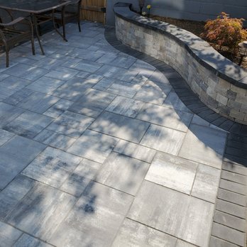 NextGen Contractors - a patio area with a brick wall and table and chairs - Masonry/Concrete Near Me