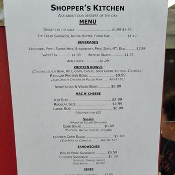 Shopper's Kitchen - Menu - The menu from Shopper's Kitchen displays various food and drink options, including sandwiches, salads, protein bowls, beverages, and desserts. It features prices for each item, such as pulled pork sandwich for $5.59, cobb salad for $8.49, and drinks like lemonade for $1.99. The menu emphasizes options for different dietary preferences, including vegetarian and vegan bowls, and offers add-ons like meat for an additional cost. The menu is printed on a white sheet with black text, set against a red background. - Desserts Near Me - Topeka, Kansas