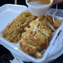a hand holding a cup of coffee over a tray of food