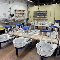 House of Clay - Our wheel throwing studio set up and ready for class, with multiple pottery wheels, stools, tools, and glaze shelves in a clean, welcoming s