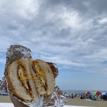 North Eats - a person holding a hot dog on a beach - Food Stands Near Me - Asbury Park, New Jersey North Eats - a person holding a hot dog on a beach - Food Stands Near Me - Asbury Park, New Jersey