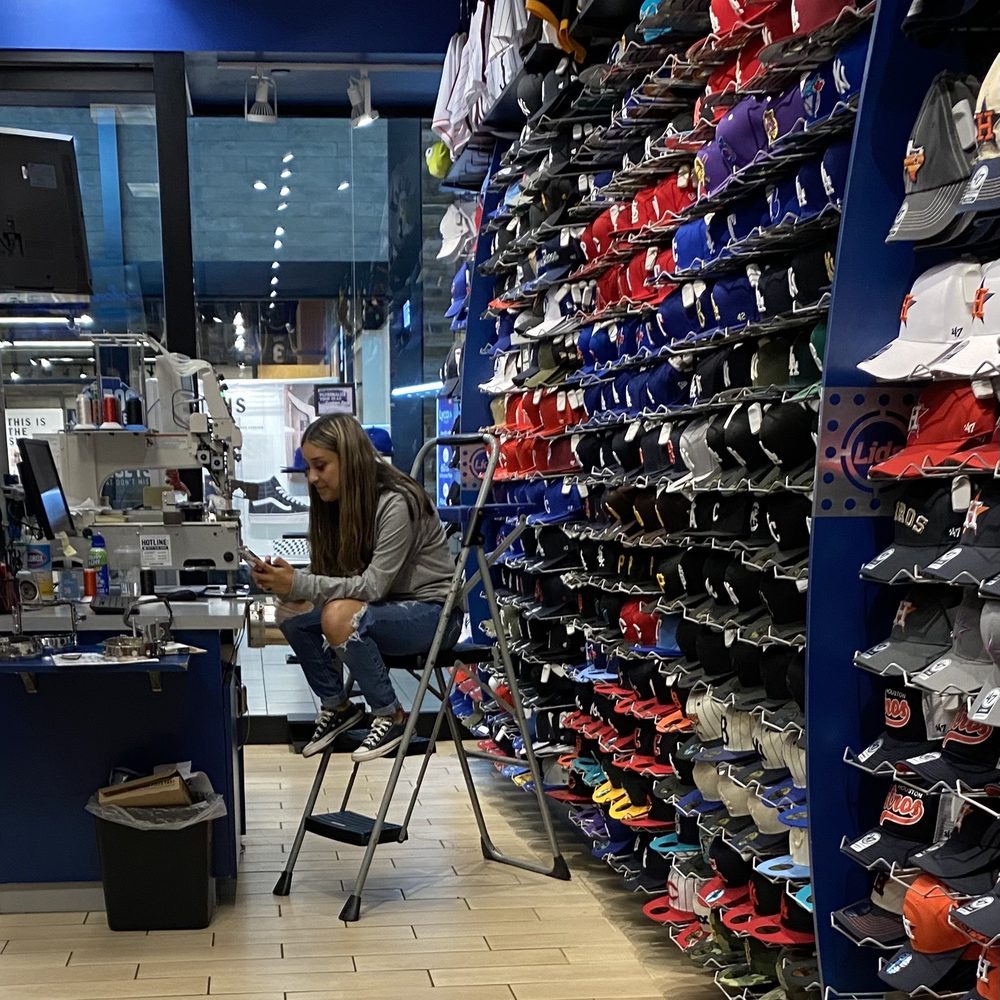 Lids - Employee texting, texting, texting. - Sports Wear Near Me - Houston, Texas Lids - Employee texting, texting, texting. - Sports Wear Near Me - Houston, Texas