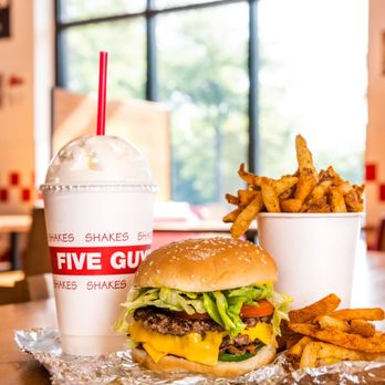 Five Guys - A Five Guys cheeseburger, milkshake and regular order of fries sits on a table inside a Five Guys restaurant. - Burgers Near Me - Winston Salem, North Carolina