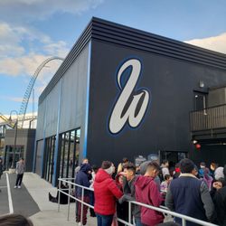 West Coast Racers - Outside in line at West Coast Racers. The building resembles a garage.
