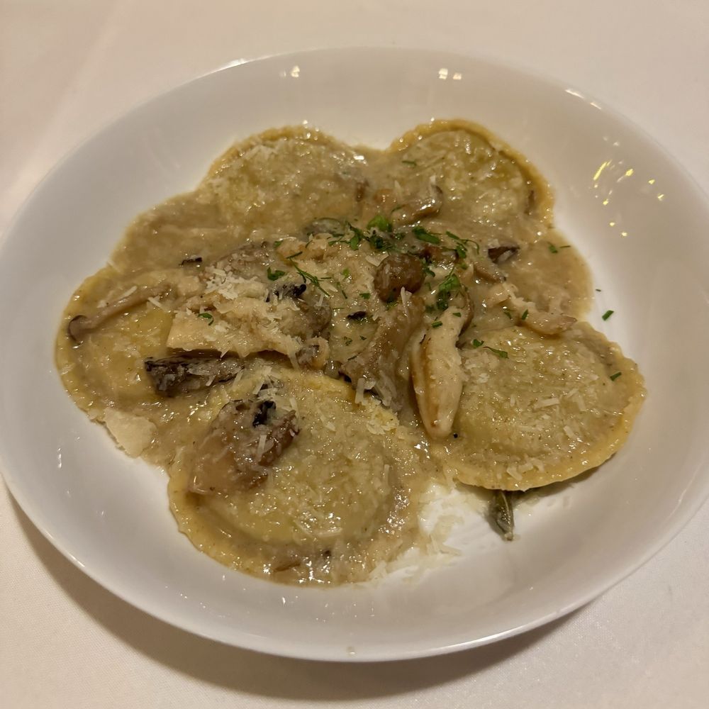 Mushroom risotto on a white plate on a white tablecloth