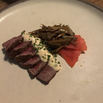 Uchi Austin - Wagyu - A plate features sliced cooked beef topped with a white sauce and chopped chives, alongside sautéed mushrooms and pickled vegetables. - Sushi Bars Near Me - Austin, Texas