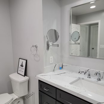 Excell Construction - a bathroom with a toilet, sink, and mirror - General Contractors Near Me - Ontario, California Excell Construction - a bathroom with a toilet, sink, and mirror - General Contractors Near Me - Ontario, California