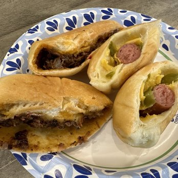Glaze - A paper plate holds three breakfast sandwiches with sausage, green peppers, and caramelized onions, served on a wooden table. - Donuts Near Me - Katy, Texas