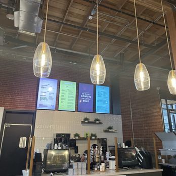 Creampuff - Inside - A donut shop interior featuring digital menu screens, pendant lights, and a counter with equipment and staff. - Donuts Near Me - Phoenix, Arizona
