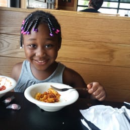 a little girl sitting at a table with two bowls of food