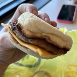 a hand holding a sausage sandwich