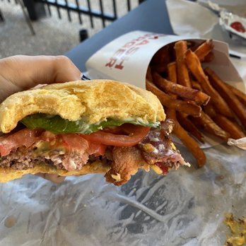 Smashburger - a hand holding a half eaten sandwich - Burgers Near Me - Warwick, Rhode Island