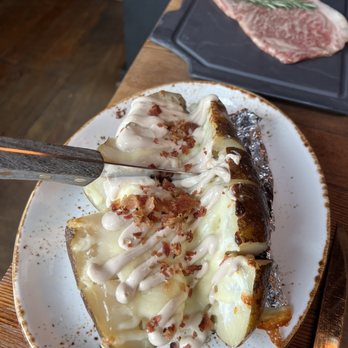 Asadero Ballard - Giant potato with the table side steak in the background - Mexican Near Me - Seattle, Washington Asadero Ballard - Giant potato with the table side steak in the background - Mexican Near Me - Seattle, Washington