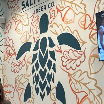 Salty Turtle - Raleigh Taproom - a woman standing in front of a wall mural - Breweries Near Me
