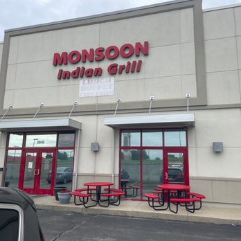 Monsoon Grill - Exterior view of Monsoon Indian Grill, showing its signage, entrance, and outdoor red picnic tables in a shopping plaza. - Indian Near Me - Topeka, Kansas