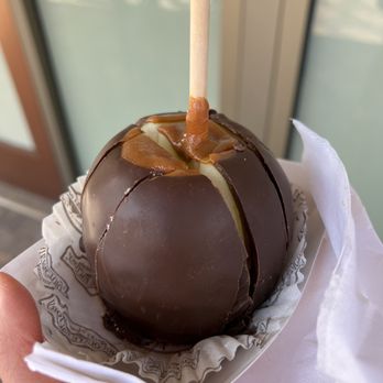 Rocky Mountain Chocolate Factory, Citadel Outlets - a hand holding a chocolate covered caramel - Chocolatiers & Shops Near Me - Commerce, California Rocky Mountain Chocolate Factory, Citadel Outlets - a hand holding a chocolate covered caramel - Chocolatiers & Shops Near Me - Commerce, California