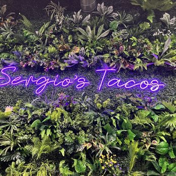 Sergio’s Tacos - a neon sign in front of a wall of plants - Tacos Near Me - Titusville, Florida Sergio’s Tacos - a neon sign in front of a wall of plants - Tacos Near Me - Titusville, Florida