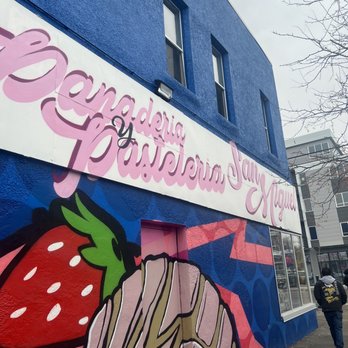Panaderia San Miguel - a woman walking past a painted building - Bakeries Near Me - Minneapolis, Minnesota Panaderia San Miguel - a woman walking past a painted building - Bakeries Near Me - Minneapolis, Minnesota