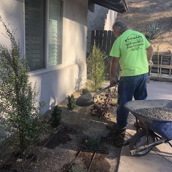 Premier Tree & Landscape - A Premier worker laying pea gravel over top irrigation lines. - Tree Services Near Me