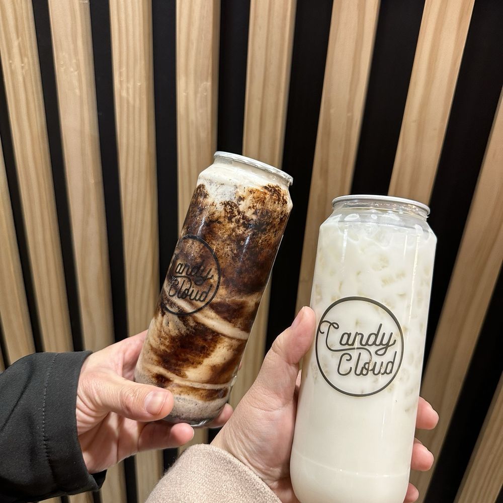 a hand holding a drink and a can a hand holding a drink and a can