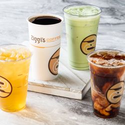 Assortment of Ziggi's drinks on a marble surface: hot coffee, iced matcha, iced dark coffee, and a yellow iced tea drink.