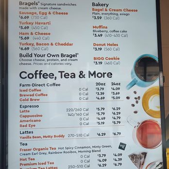 Biggby Coffee - Menu 2/20/2026 - The menu board from Biggby Coffee lists breakfast sandwiches such as sausage, egg, and cheese, turkey havarti, ham and cheese, and turkey, bacon, and cheddar. It also offers baked goods including bagels with cream cheese, muffins, donut holes, and a Bigg Cookie. The coffee and tea section includes farm-direct coffee, espresso drinks like latte, cappuccino, americano, and red eye, as well as teas like Fraser Organic Tea, hot tea, and premium iced tea. Prices and calorie counts are provided for each item, with some options available in different sizes. The board emphasizes nutritional details and variety of breakfast and beverage options. - Coffee & Tea Near Me - Itasca, Illinois