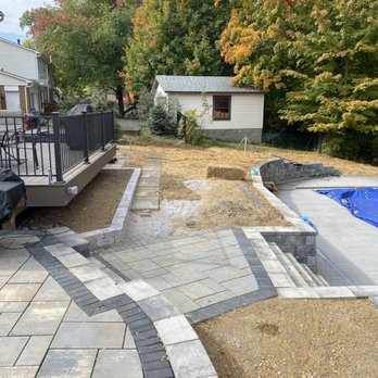Grizscapes - Raised Unilock patio over looking fiberglass pool - Landscaping Near Me