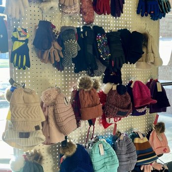 Turn Style Consignment - Winter Hats & Gloves - A pegboard showcases an assortment of winter hats and gloves, including beanies, knit caps, and mittens, arranged in rows. - Used, Vintage & Consignment Near Me - Maple Grove, Minnesota