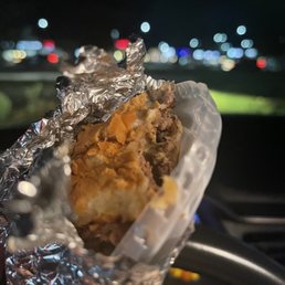 a hand holding a sandwich wrapped in tin foil a hand holding a sandwich wrapped in tin foil