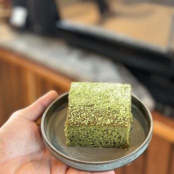 Composition Coffee - a person holding a plate of matcha cake - Coffee & Tea Near Me - West Palm Beach, Florida Composition Coffee - a person holding a plate of matcha cake - Coffee & Tea Near Me - West Palm Beach, Florida